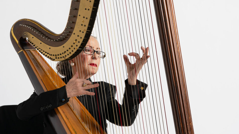 woman playing harp in front of white background