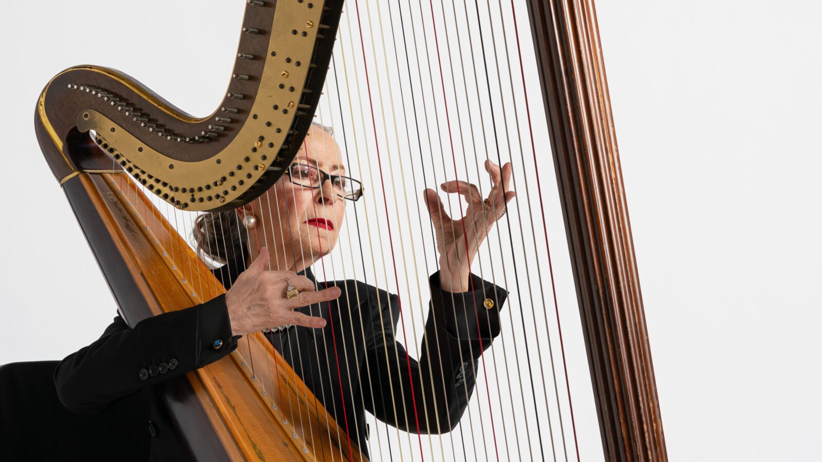 woman playing harp in front of white background