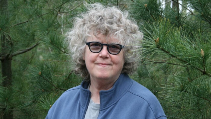 gray haired woman in glasses looks into camera