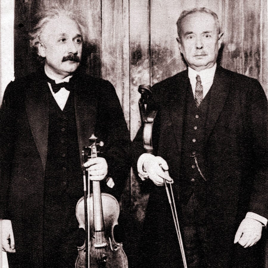 Two well dressed men holding violins