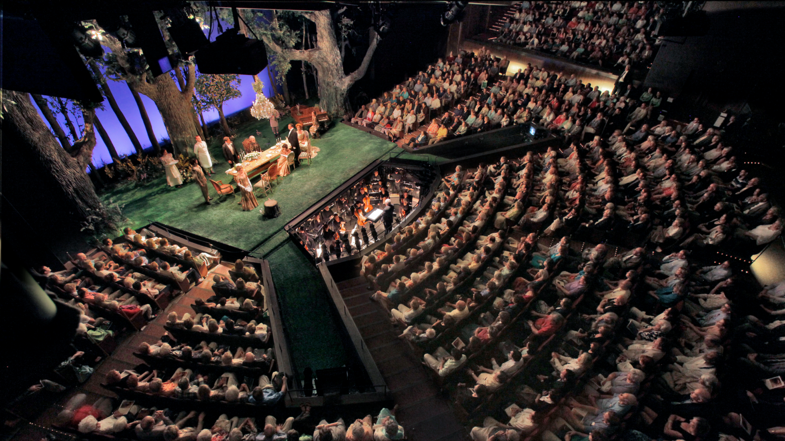 Overhead view of The Virginia Jackson Browning Theater during a performance, the stage in the upper left corner of the frame with the audience fanning out in concentric rows.