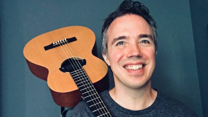 grinning man with guitar on his shoulder