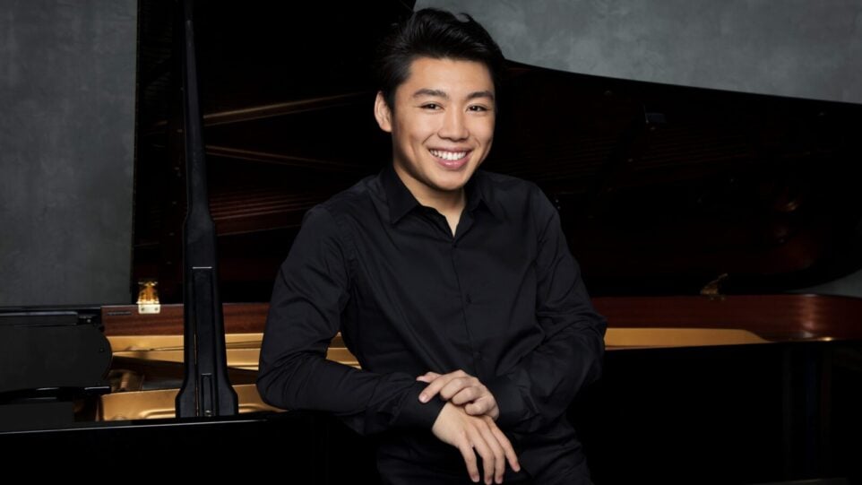 Pianist in black shirt leans against instrument