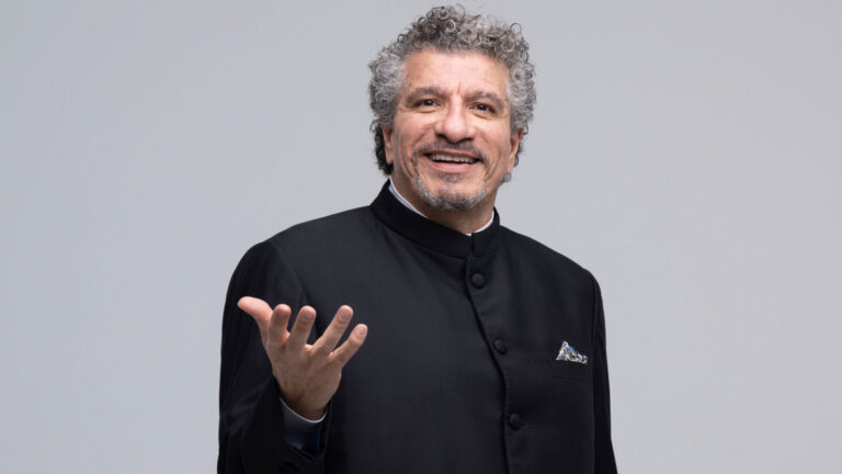 Man in dark coat gestures excitedly