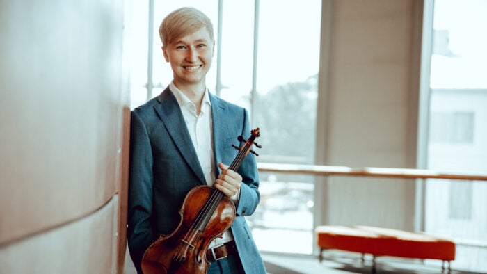 Young person in suit holds violin