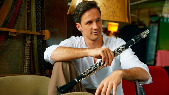 Man in white shirt holds clarinet