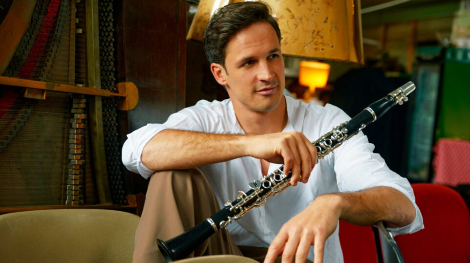 Man in white shirt holds clarinet