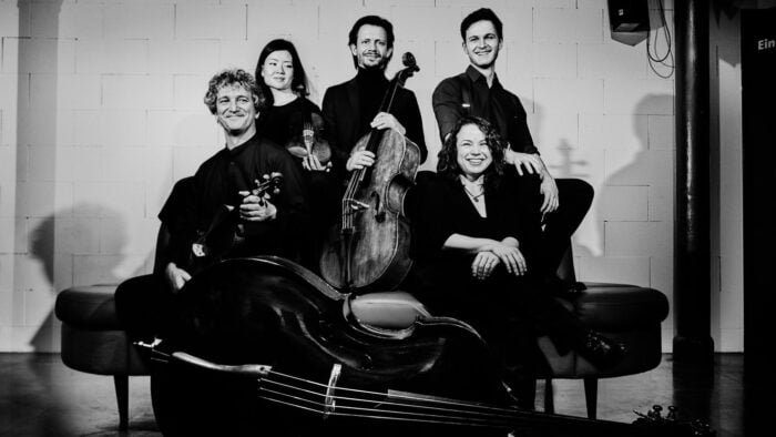 Musicians in black and white in front of white wall