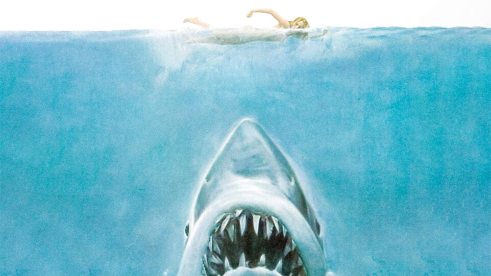closeup of Jaws poster features woman swimming in open water... with shark lurking below
