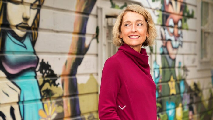 Woman in fuchsia shirt poses in front of colorful wall