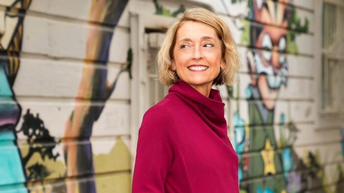 Woman in fuchsia shirt poses in front of colorful wall