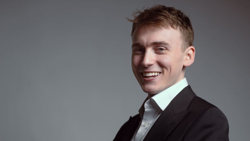 young man in suit grins widely