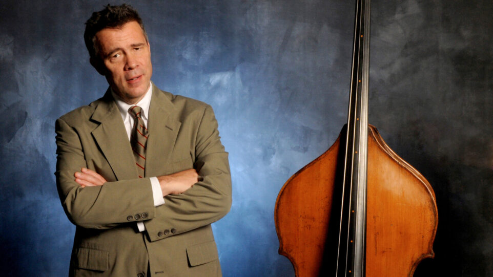 Man in olive suit poses with double bass
