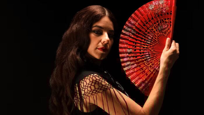 darkly lit woman with red fan