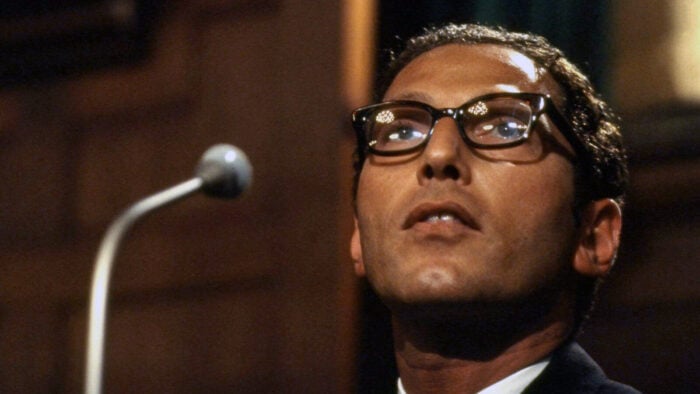 closeup of man in suit and glasses onstage