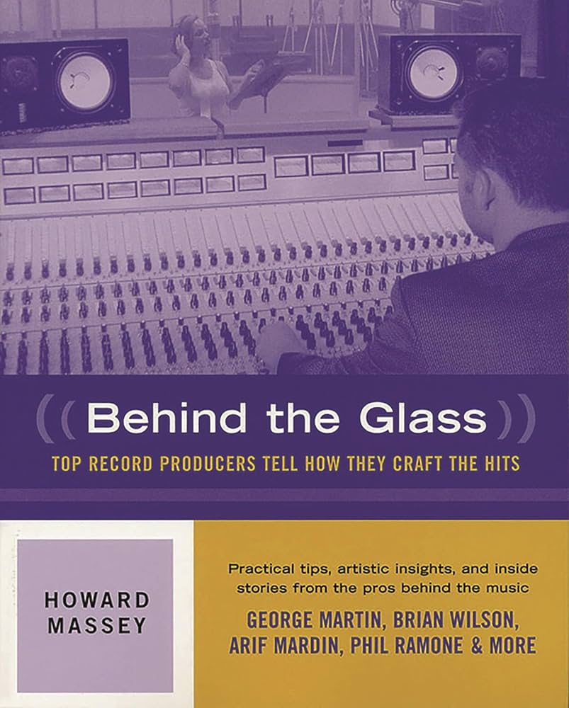 man leaning over audio control board with woman performing on other side of studio glass