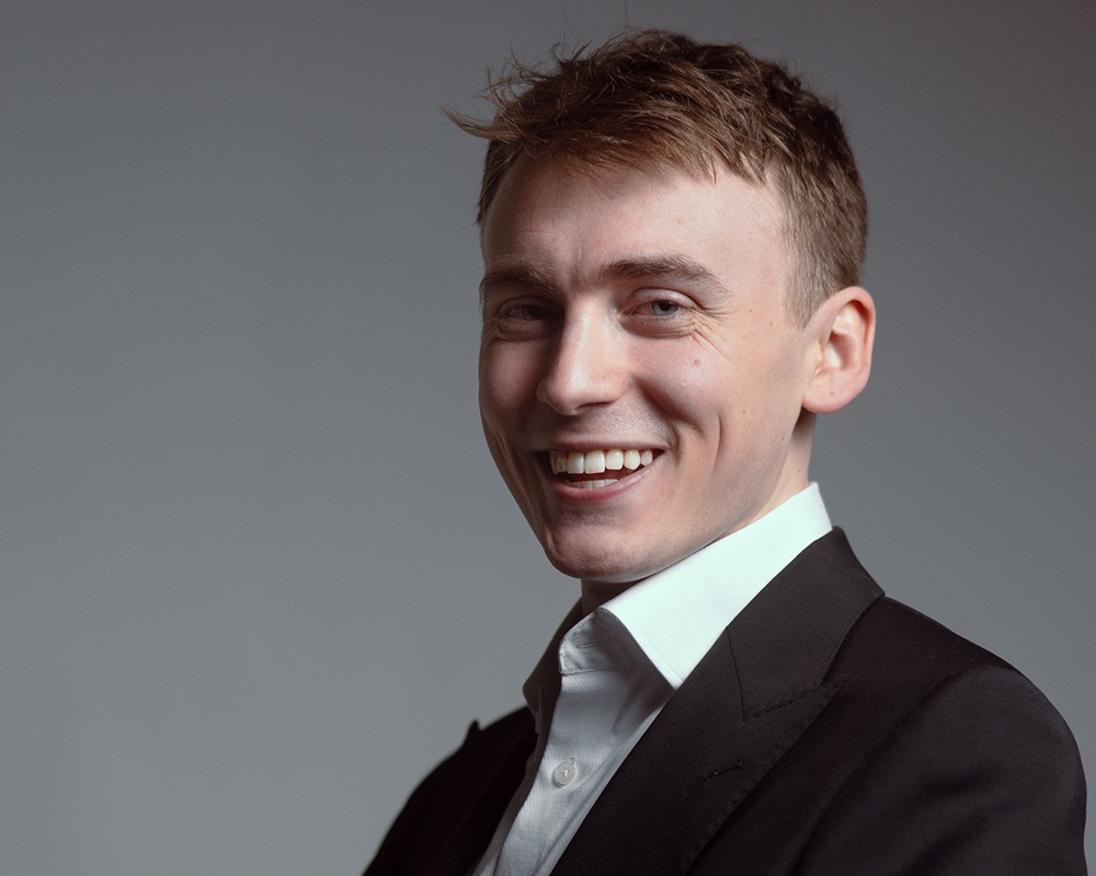 young man in suit grins widely