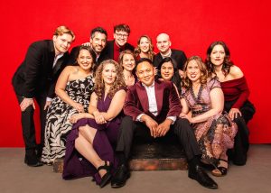 Members of Chicago a cappella pose in front of a red background