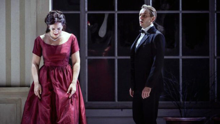 agitated looking man in tuxedo and woman in wine red formal dress