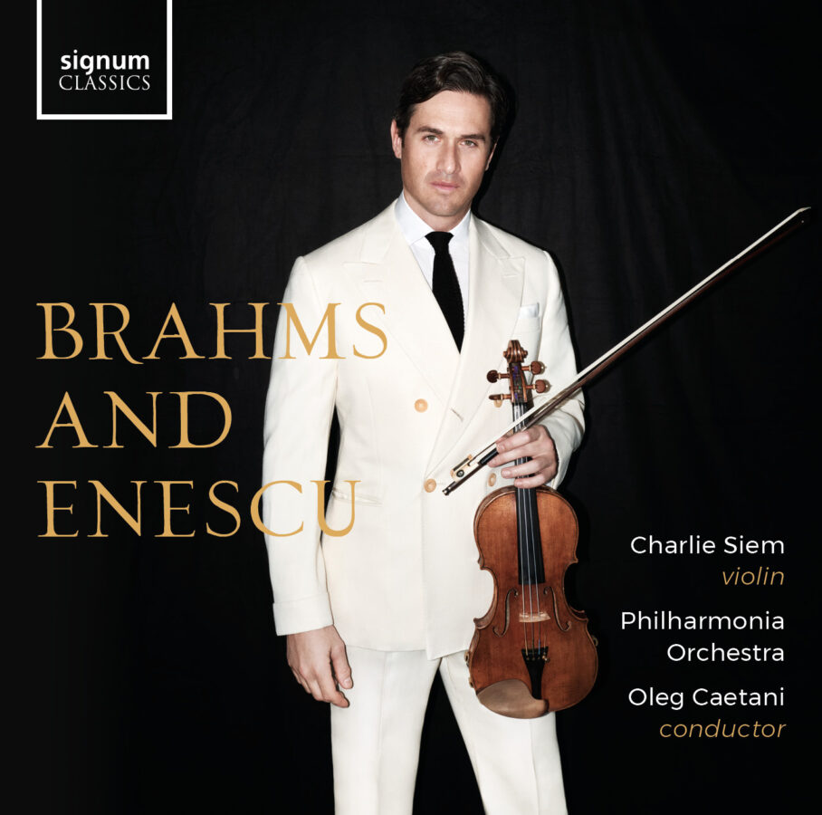 Man in cream suit and black tie holds violin