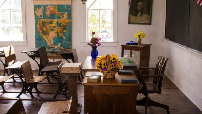 School Class Room with wooden desks, a map, and a black board