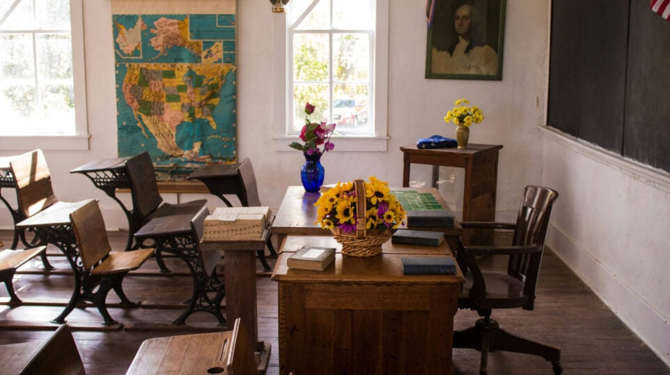 School Class Room with wooden desks, a map, and a black board