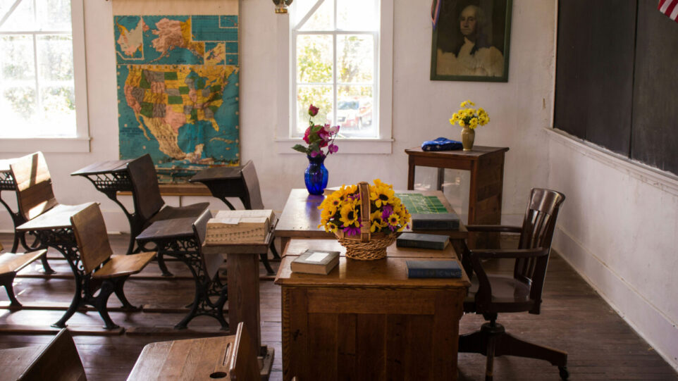 School Class Room with wooden desks, a map, and a black board