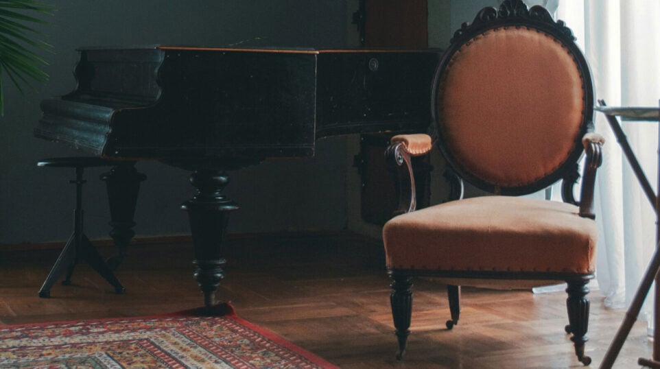 A Piano in a living room with a nice chair next to the piano