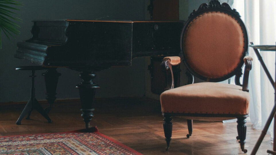 A Piano in a living room with a nice chair next to the piano