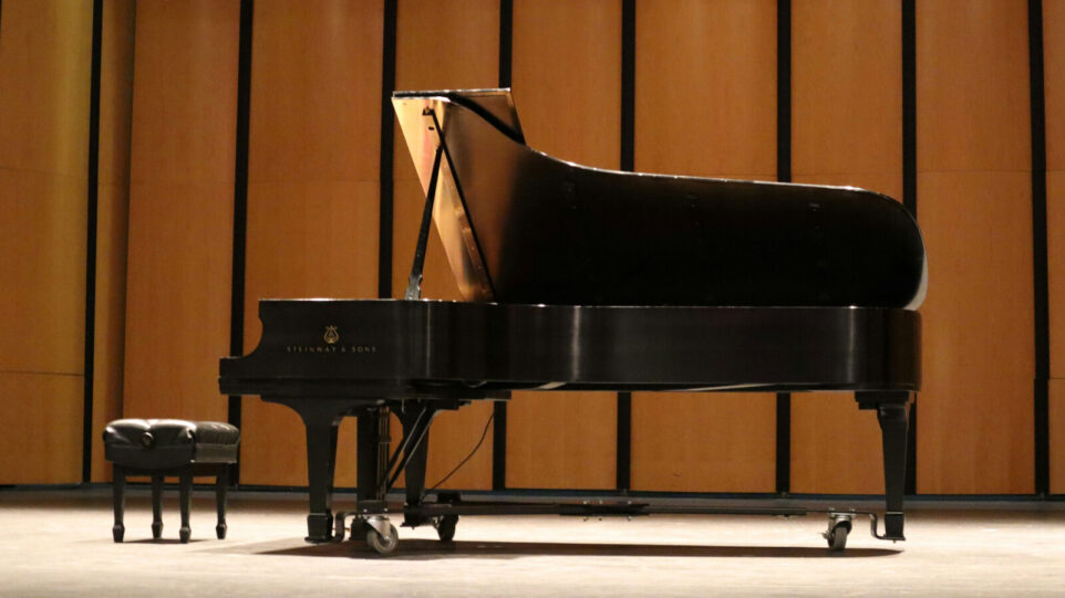 A Grand Piano on Stage with a gold backdrop
