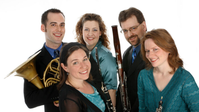 Members of Quintet Attacca posing in front of white background with their instruments