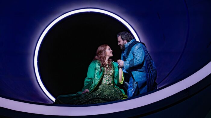 Lise Davidsen in green brocade as Isolde and Michael Spyres in blue brocade as Tristan in the Metropolitan Opera's new production of "Tristan und Isolde." The production seems to have a minimalist set with bold ligthing design.