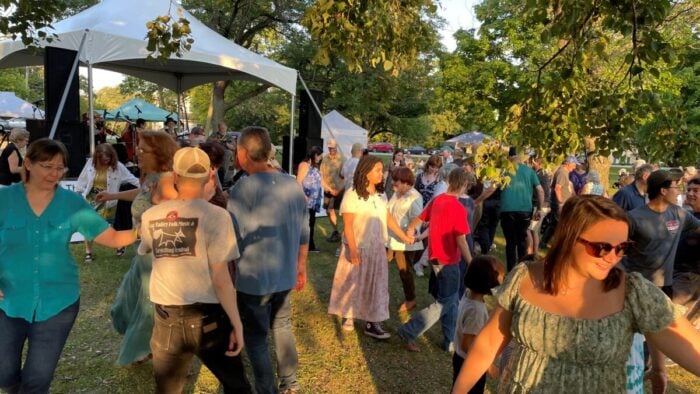 a mix of people square dance outdoors