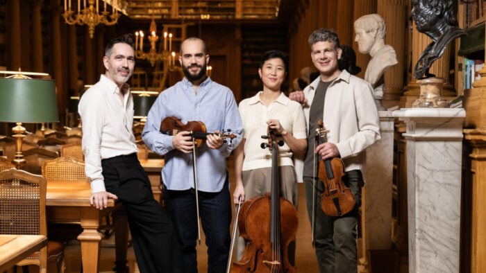 four musicians holding their instruments and smiling