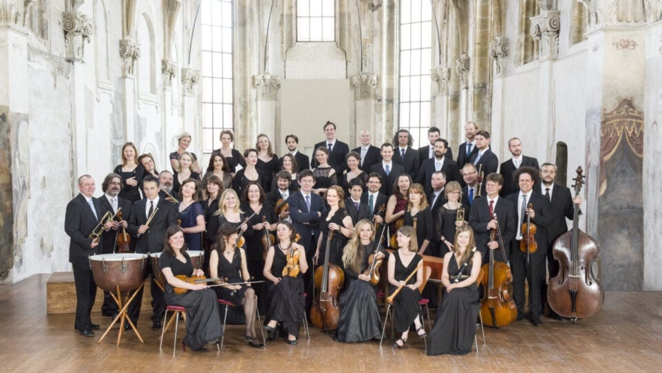 musicians with their instruments surrounding their conductor
