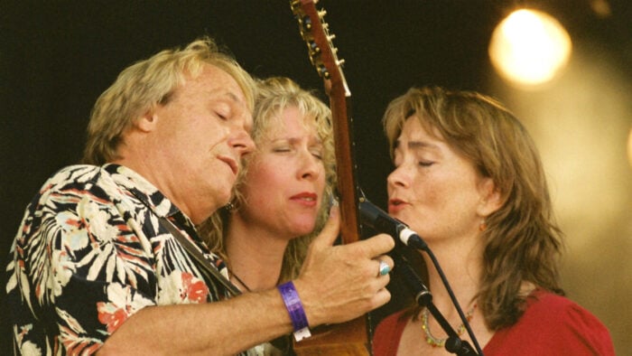 man and two women sing into one microphone
