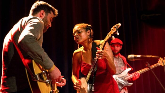 man plays guitar, woman plays banjo, bass player in background