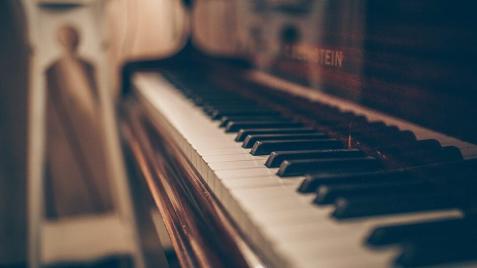 A view of the piano keys of a brown, upright piano.