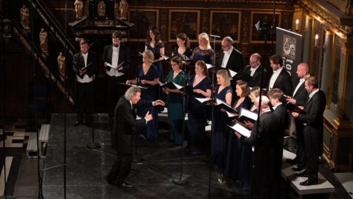 A man conducts a choir of men and women in a church
