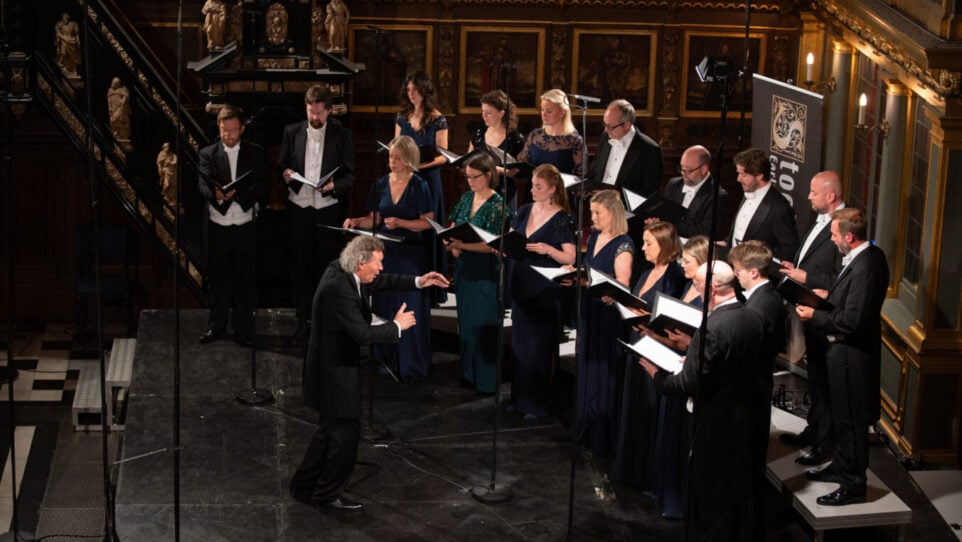 A man conducts a choir of men and women in a church