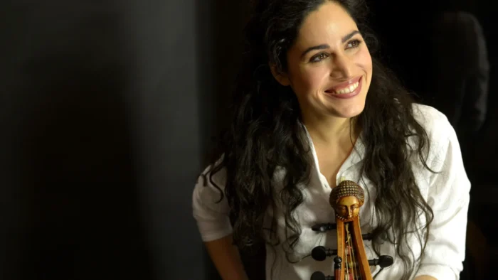 A young woman holding a viola da gamba smiles