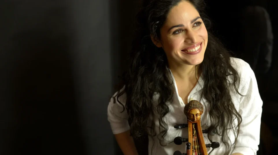 A young woman holding a viola da gamba smiles