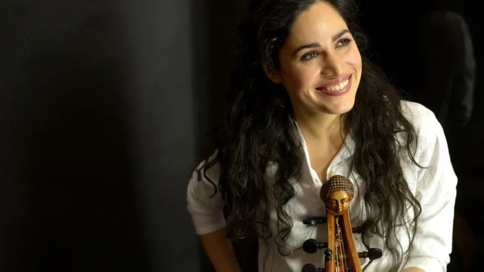 A young woman holding a viola da gamba smiles
