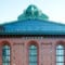 A straight-on shot of the Chicago Public Library's Harold Washington Library, a tall stout brick building with a glass and mint-copper top